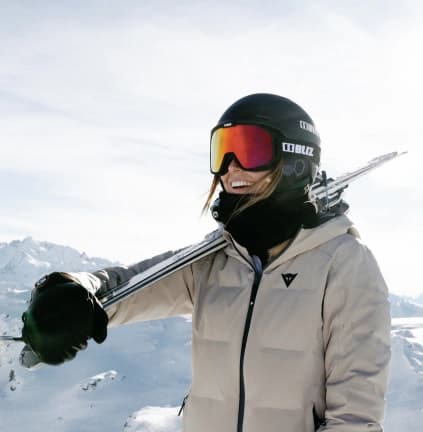 Helmet and goggles, skis on shoulder